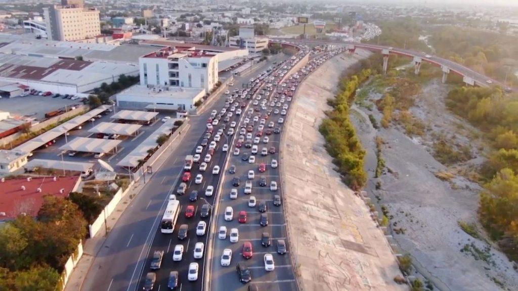 Aerial Drone View of a Congested Multi-lane Highway Next to a Concrete Embankment and a Rising Bridge in a Cityscape. - Enbroncados