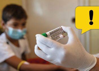 Medical Worker in a Mask and Gloves Holding Vaccine Vials, with a Yellow Warning Bubble in the Corner. - Enbroncados