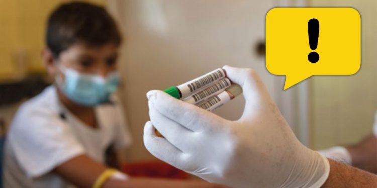 Medical Worker in a Mask and Gloves Holding Vaccine Vials, with a Yellow Warning Bubble in the Corner. - Enbroncados