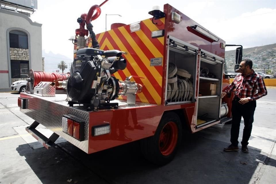 Image - Enbroncados Red Fire Truck with Yellow Diagonal Stripes and Open Compartments Displaying Hoses and Equipment, Man in Plaid Shirt Standing Beside It in a Parking Lot - Enbroncados
