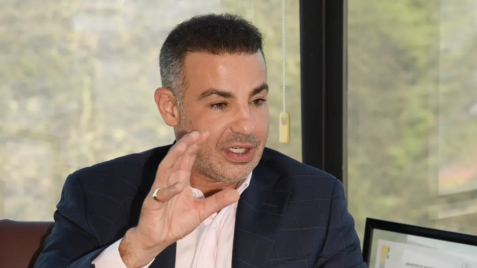 Man in a Dark Suit Speaking or Gesturing with His Right Hand During a Discussion in an Office Setting. - Enbroncados