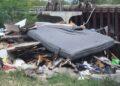 Pile of Trash and a Large Discarded Mattress Wedged Under a Bridge or Overpass. - Enbroncados