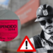 Construction Worker in a Helmet and Sunglasses Beside a Large Red 'suspendido' Notice and a Red Warning Triangle, Signaling a Suspended Work Permit at a Site. - Enbroncados