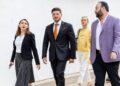 Samuel García Viste Traje Negro Con Corbata Naranja Mientras Camina Al Aire Libre Junto a Colaboradores Y Funcionarios - Enbroncados