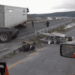 Semi-trailer Obstructing a Curved Highway with Scattered Debris and Damaged Guardrails; Two People Assess the Scene, with a Truck Side Mirror Visible in the Foreground. - Enbroncados
